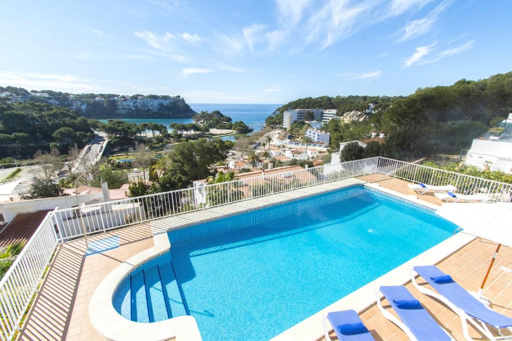 uma piscina com cadeiras e vista para o oceano em Collmar by Sonne Villas em Cala Galdana