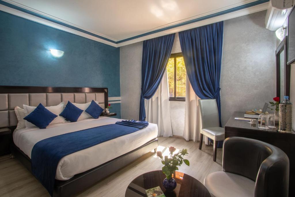 a bedroom with a bed with blue walls and a table at Hotel Meriem Marrakech in Marrakech