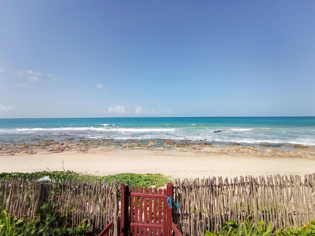 una valla de madera en la playa con el océano en Casa dos Ximenes - Beira Mar da Taíba - Ótima localização en Taíba