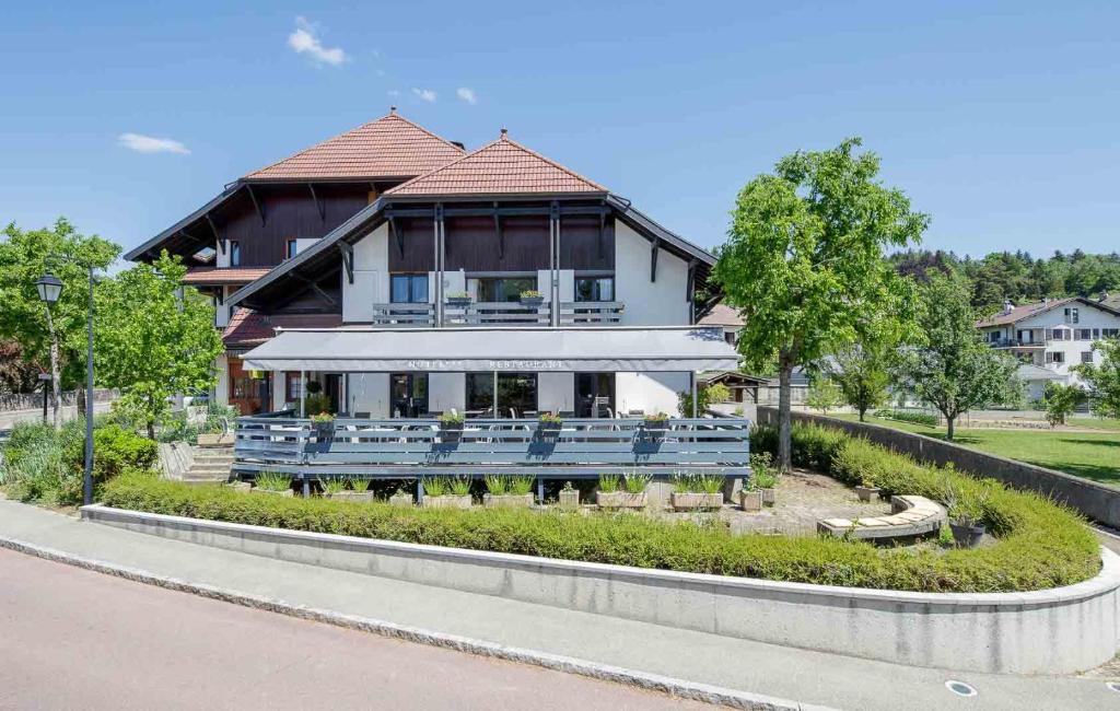 une grande maison avec bancs devant elle dans l'établissement Logis hôtel Annecy nord / Argonay, à Argonay