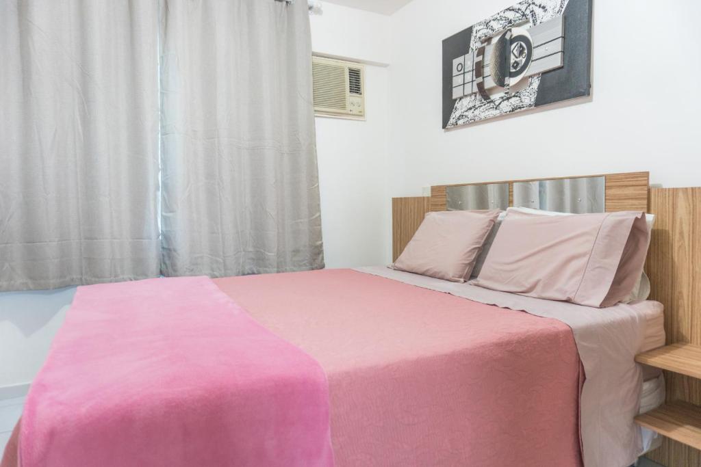 1 dormitorio con cama rosa y ventana en 4let Natal Verano, en Natal