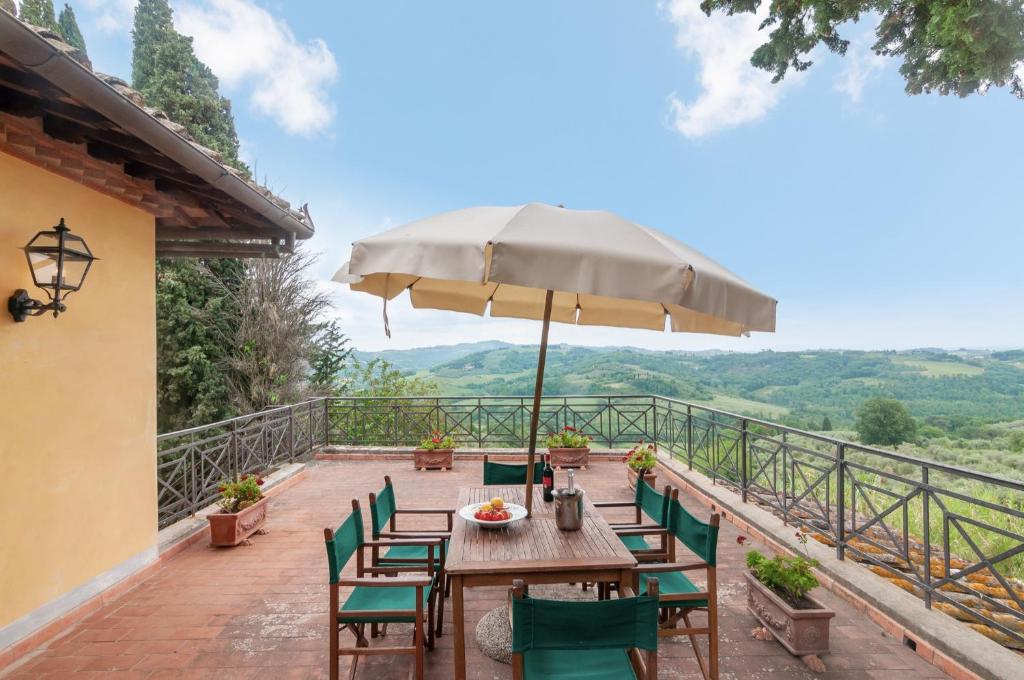 einen Holztisch und Stühle mit Sonnenschirm auf einer Terrasse in der Unterkunft Fattoria la Gigliola - La Terrazza in Montespertoli