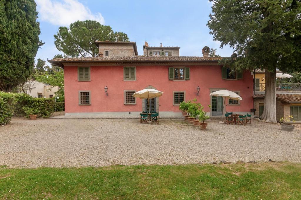 una gran casa roja con sombrillas en un patio en Fattoria la Gigliola - Il Fattore, en Montespertoli