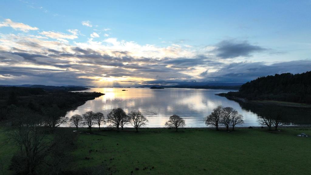 a view of a river with trees in a field at Steading Cottage - 50m from the beach in Port Appin