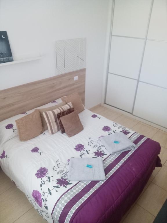 een slaapkamer met een bed met paarse en paarse lakens bij Habitación Privada May in Vecindario