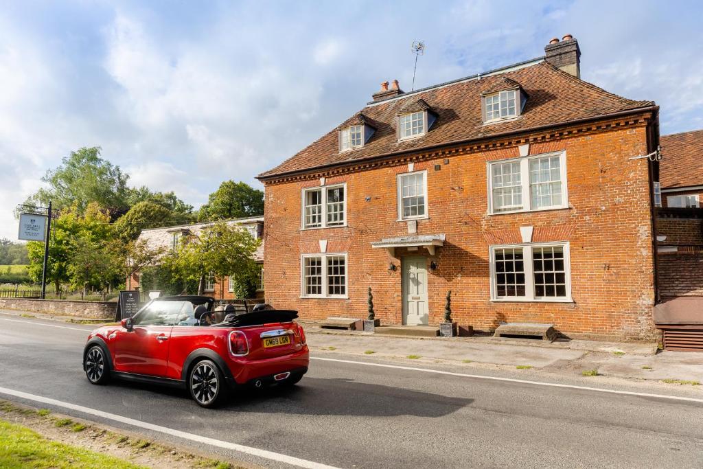 a red car driving past a brick building at The Bell Inn Hotel in Lyndhurst