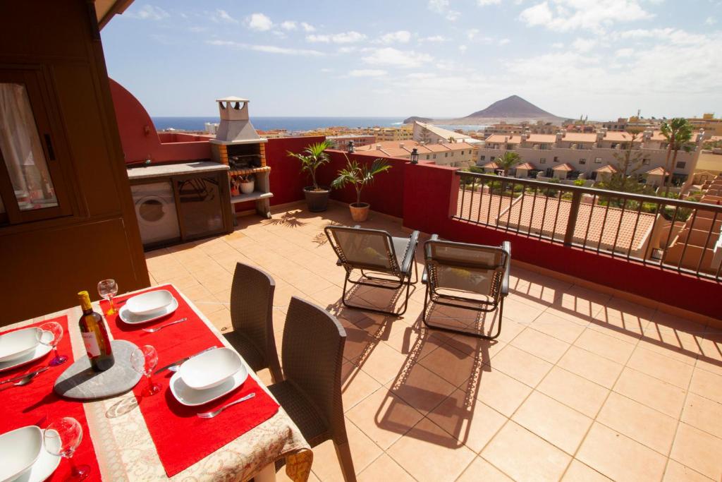 d'une table et de chaises rouges sur un balcon avec vue. dans l'établissement MEDANO4YOU Mirandas Choice Penthouse, à El Médano