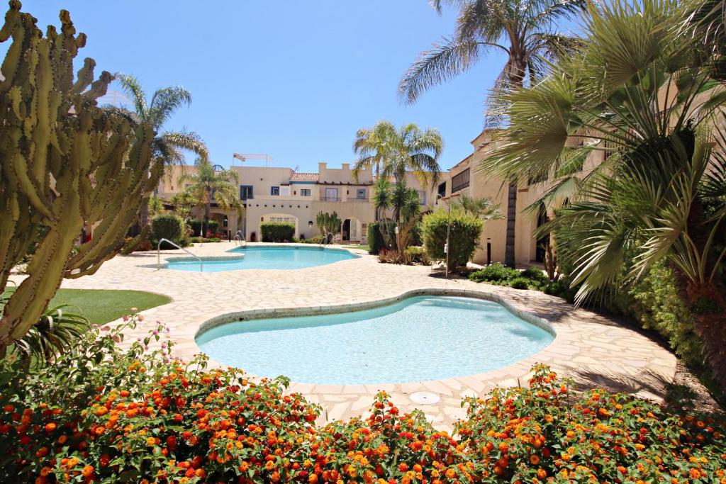 a swimming pool in a yard with palm trees and flowers at Las Casitas de la Playa in Vera