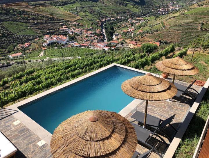 a swimming pool with two umbrellas and chairs and a swimming pool at Casa do Romezal in Peso da Régua