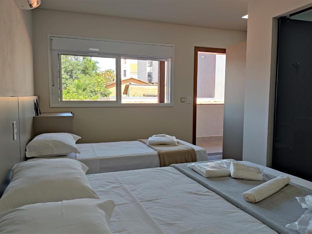 a bedroom with three beds and a window at Pousada Reserva Central in Capitólio