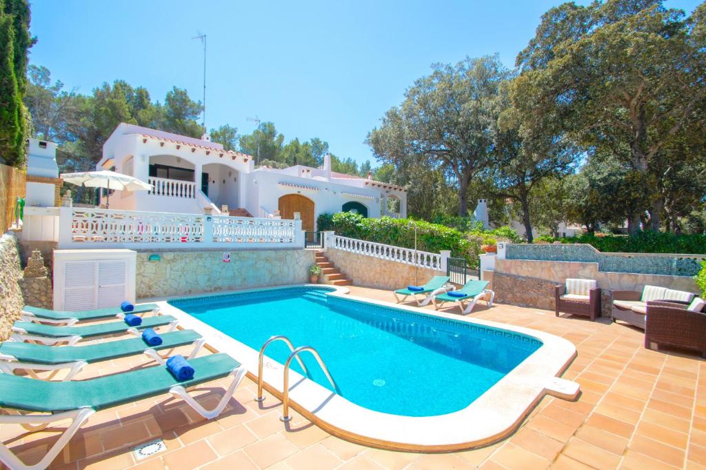 a swimming pool with lounge chairs and a house at Villa Ohana by Sonne Villas in Cala Galdana