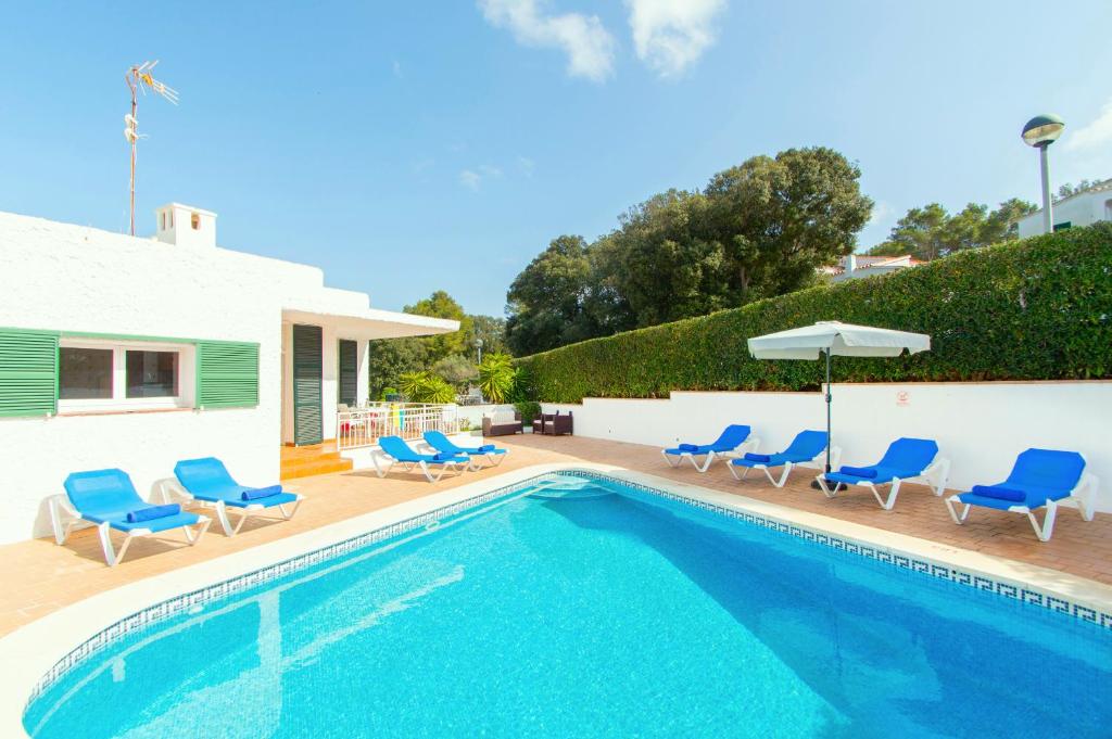 een zwembad met blauwe stoelen en een huis bij Villa Atalaia by Sonne Villas in Cala Galdana