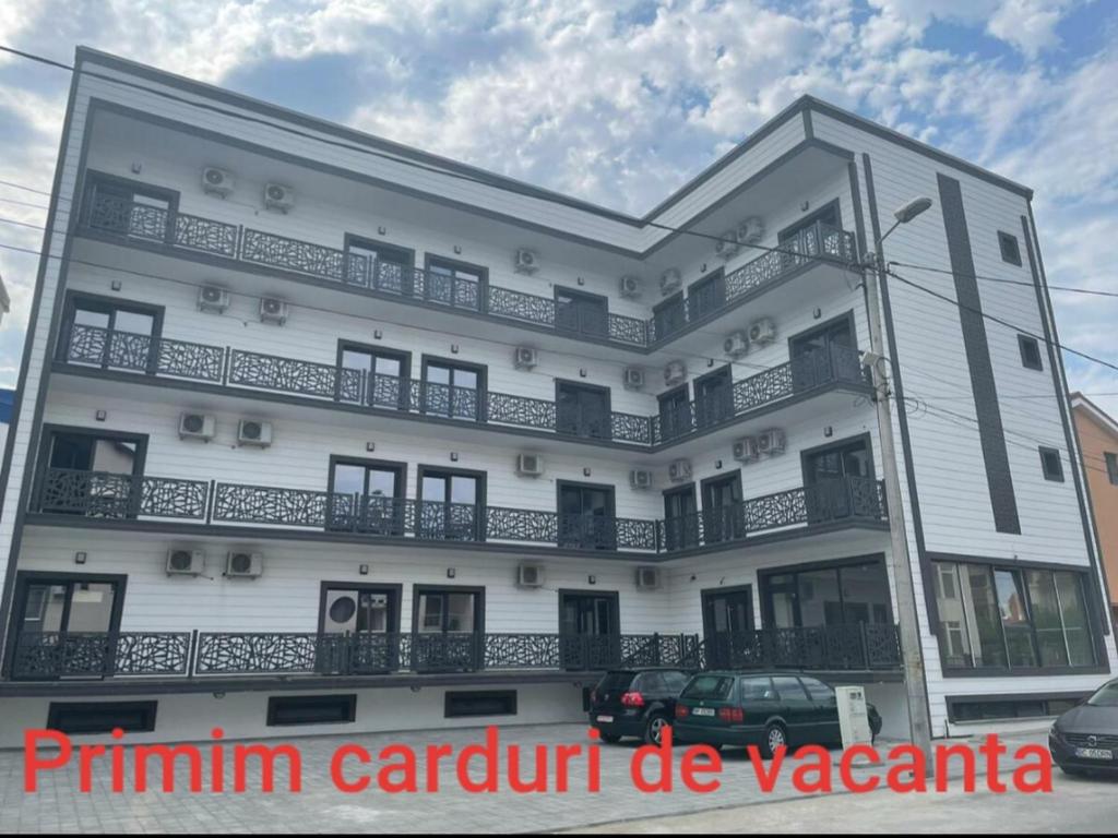 a white building with cars parked in front of it at Denis Boutique in Eforie Nord