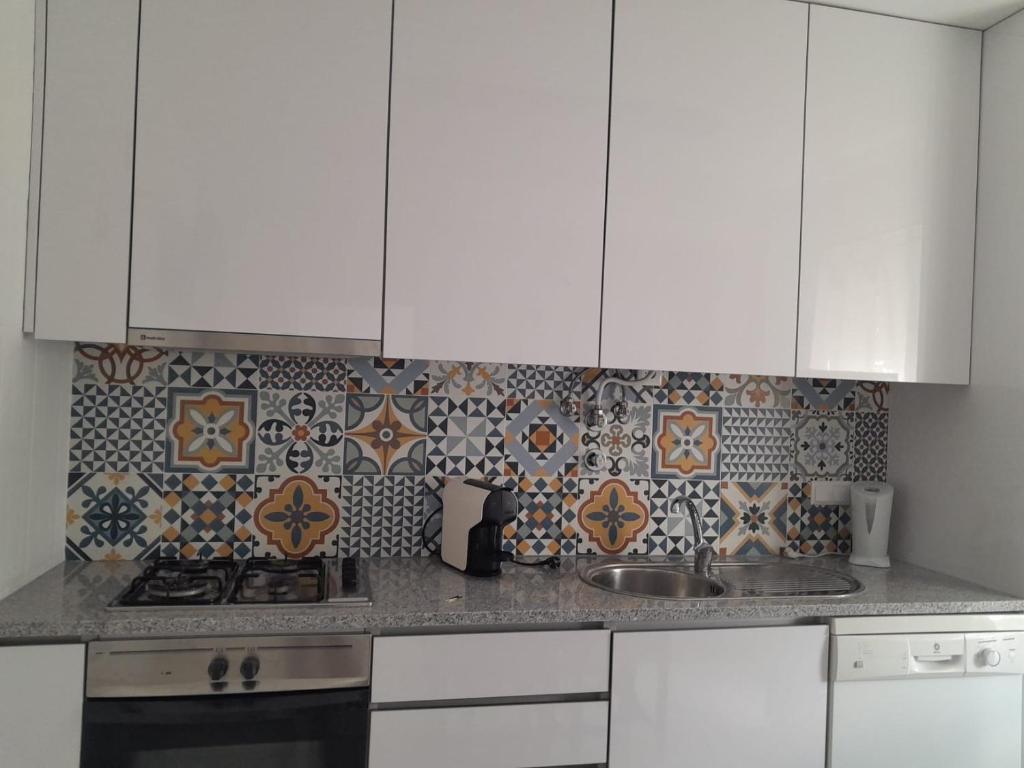uma cozinha com armários brancos e uma parede de azulejos em Casa Marques na Nazaré