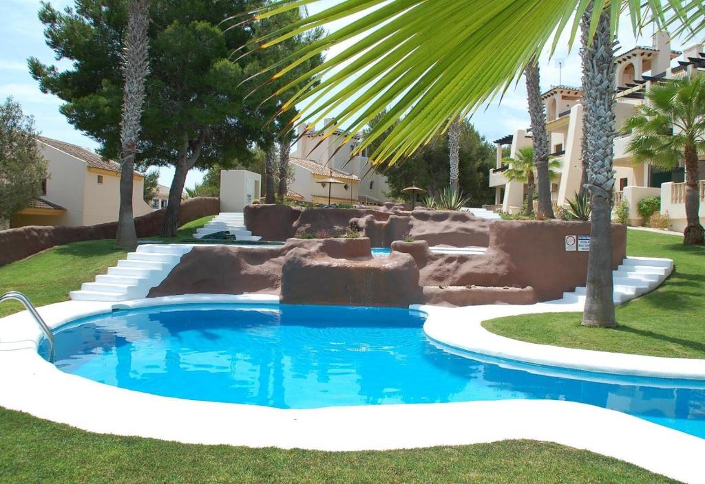 una piscina en un patio con palmeras en Lovely apartment near Golf, en Orihuela
