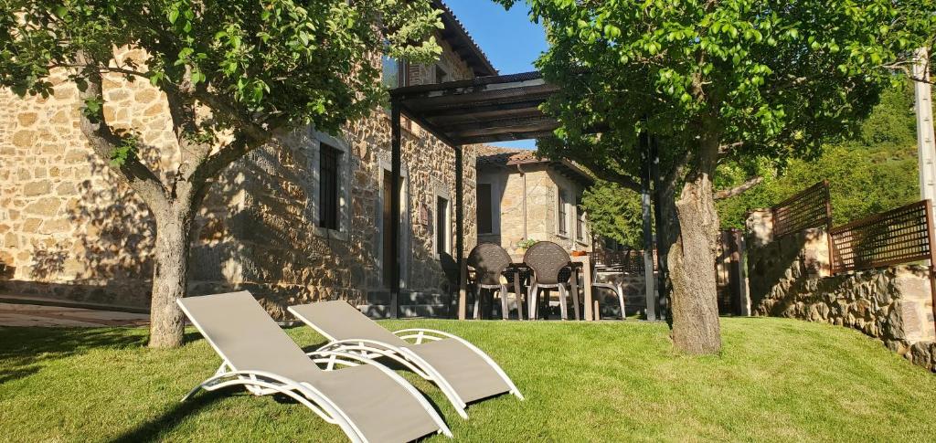 two white chairs sitting in the grass in front of a building at Casa Rural Carmen Luna in Miñera de Luna