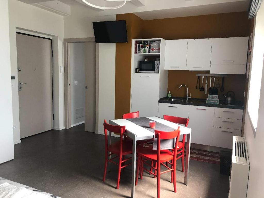eine Küche mit einem weißen Tisch und roten Stühlen in der Unterkunft Appartamenti il borgo papavero in Busca