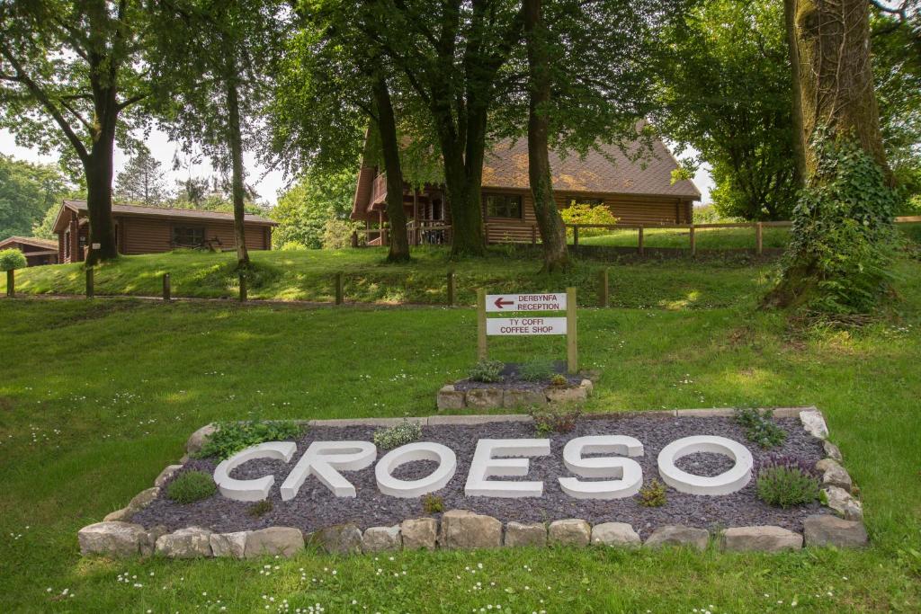 a sign in the grass with a house in the background at MBH3 Lodges at Pantglas Hall in Carmarthen