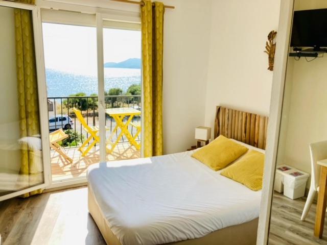 una camera con letto e un balcone con vista di Hôtel Almanarre Plage - Hôtel Eco-Responsable face à la mer a Hyères