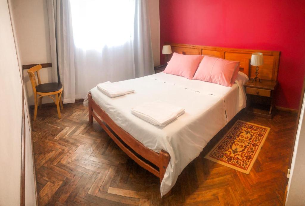 a bedroom with a large bed with a red wall at Hotel Mustapic in Ushuaia