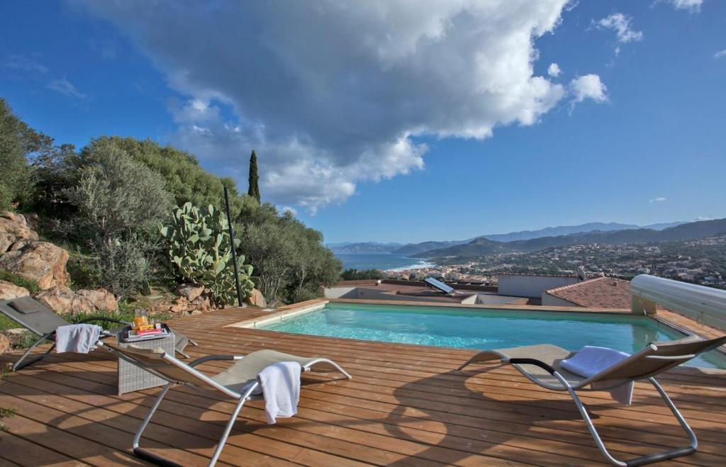 uma piscina com duas cadeiras num deque de madeira em Villa Annonciade em L'Île-Rousse