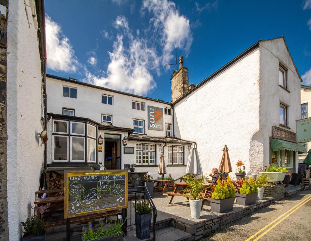 a pub with tables and umbrellas in front of a building at The Sun Boutique and Lounge in Hawkshead