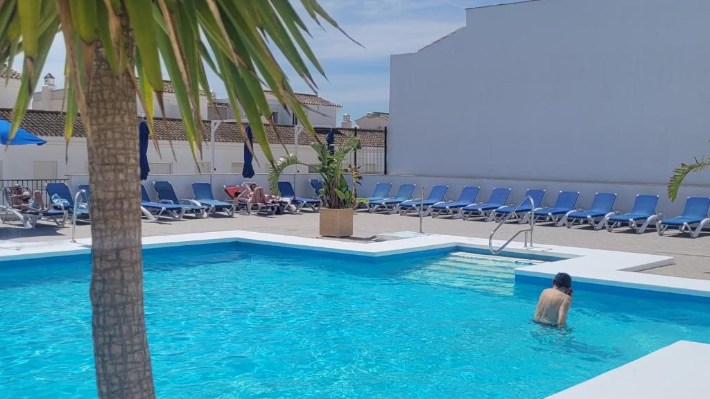 un homme dans une piscine à côté d'un palmier dans l'établissement Apartamento ClaVer, à Vejer de la Frontera
