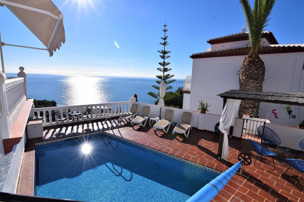 une piscine avec des chaises et l'océan en arrière-plan dans l'établissement Ladera Panorama 2, à Nerja