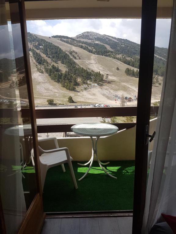 una mesa y sillas en un balcón con vistas en Studio 4 couchages vue pistes, en Gréolières les Neiges