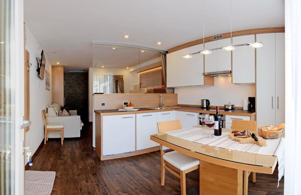 a kitchen with white cabinets and a table with chairs at Apartments Mujnei in Santa Cristina in Val Gardena