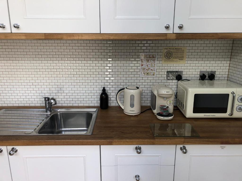 a kitchen counter with a sink and a microwave at The Beetroot in Margate
