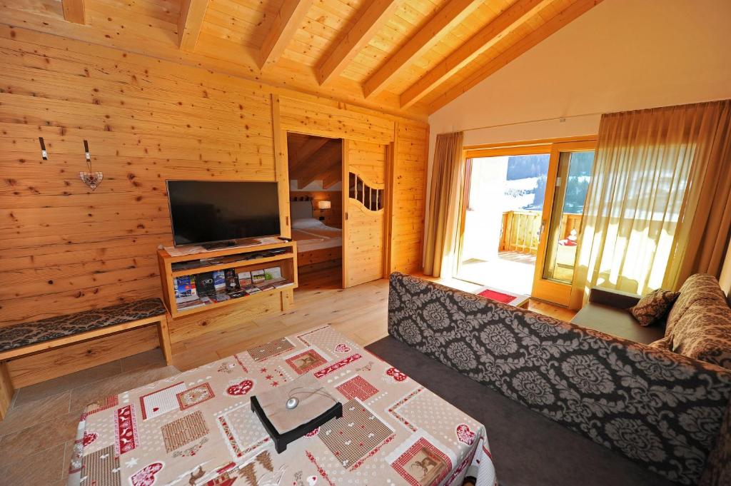 ein Wohnzimmer mit einem Sofa und einem TV in der Unterkunft Mountain Apartment Hapeli in St. Ulrich in Gröden