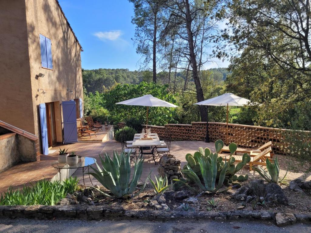 un patio avec des tables et des parasols dans une cour dans l'établissement La Commanderie, à Cotignac