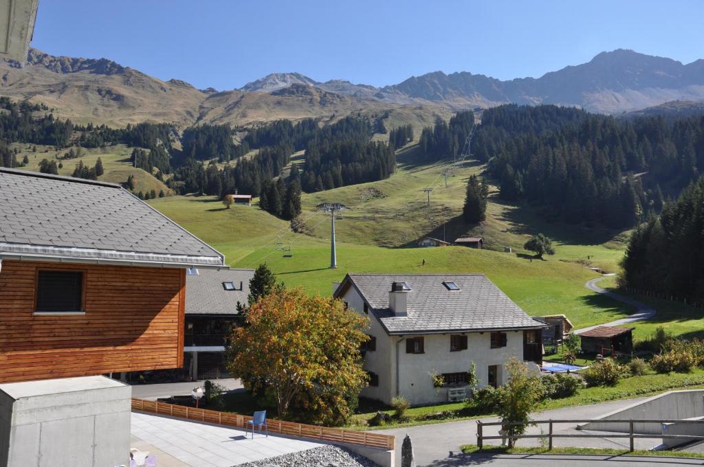 a view of a house with mountains in the background at Ski in-Ski out Apartment Heimberg-Parpan-Lenzerheide in Parpan