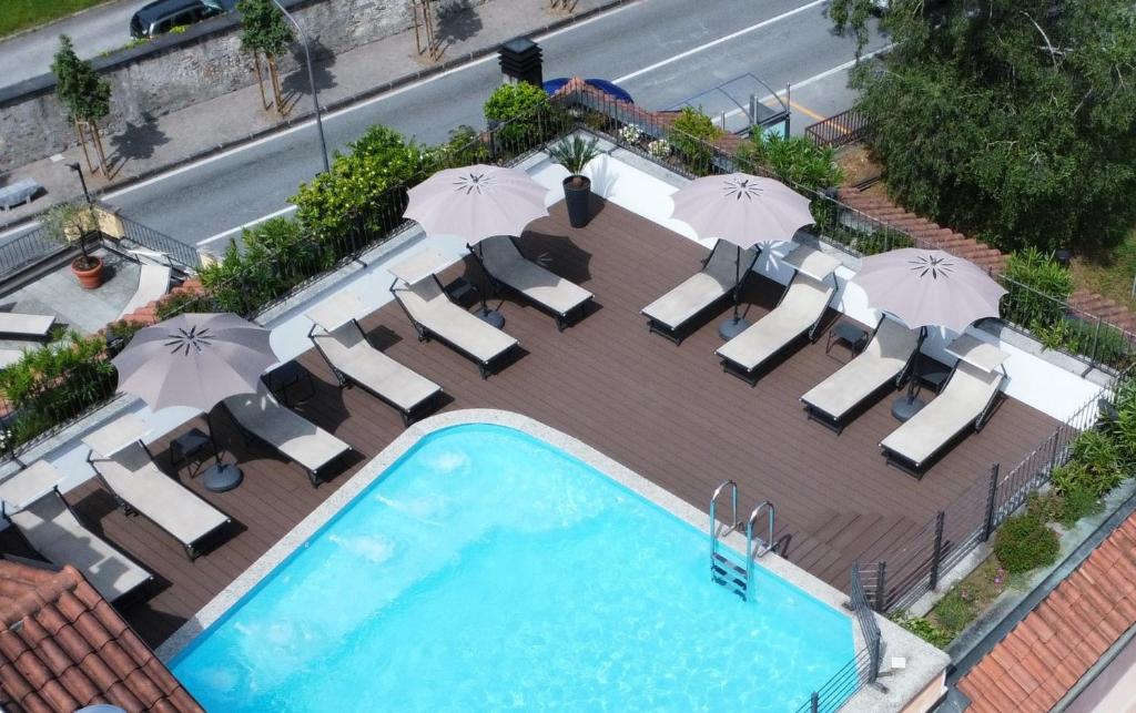 an overhead view of a swimming pool with chairs and umbrellas at Hotel Giardino in Cannobio