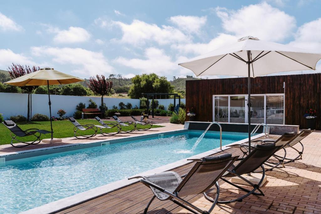 a swimming pool with chairs and an umbrella at Barrocas Village in Olho Marinho