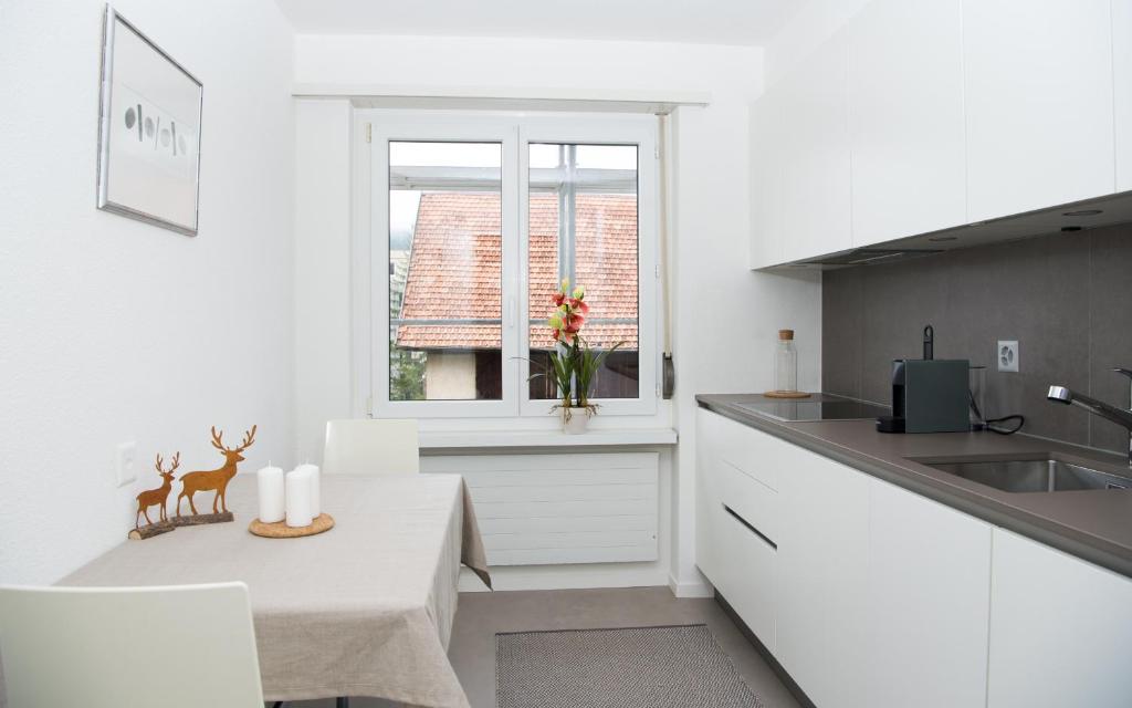 uma cozinha branca com uma mesa e uma janela em Central flat Crapera-Lenzerheide em Lenzerheide