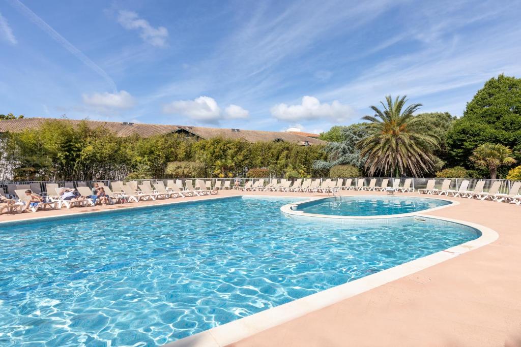 - une piscine avec des chaises et des fauteuils dans l'établissement Puchouau Appartement en Rez Jardin, à Moliets-et-Maa
