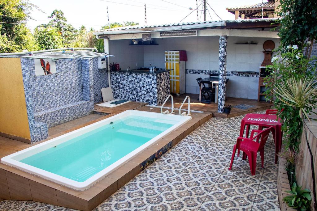 una piscina en un patio con una silla roja en Casa com Churrasqueira e Piscina em Camacari BA, en Camassari