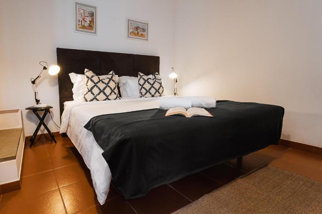 a bedroom with a large black bed with two books on it at Óbidos Priest Room in Óbidos