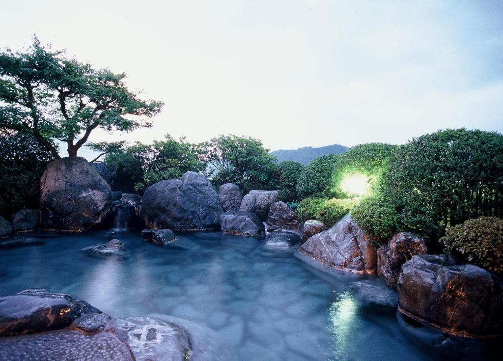 una piscina de agua con rocas y árboles en Saginoyusou, en Yasugi