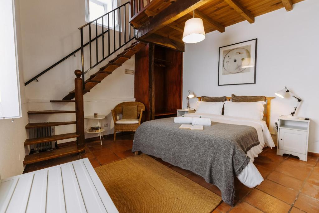 a bedroom with a large bed and a staircase at Casa António Moreira in Óbidos