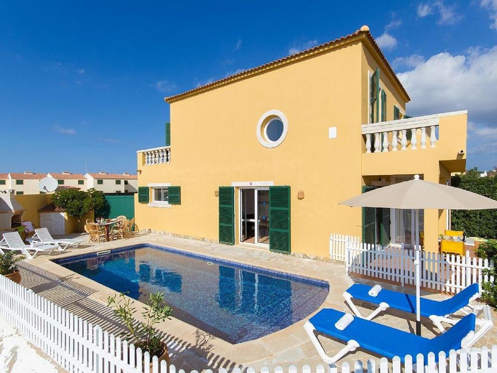 a villa with a swimming pool in front of a house at Villa Fiesta in Ciutadella