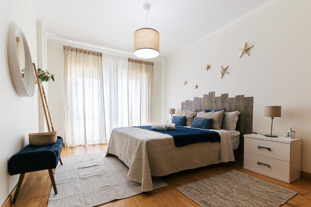 a white bedroom with a large bed and a chair at Baleal Beachfront Apartment in Ferrel