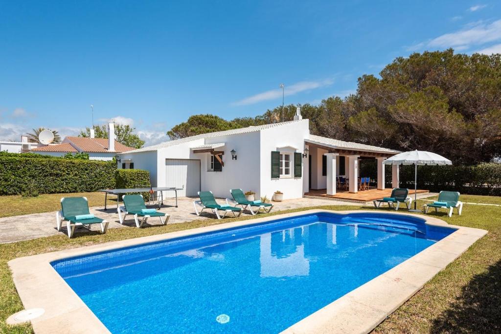 a villa with a swimming pool in front of a house at Villa Cristina in Cala en Bosc