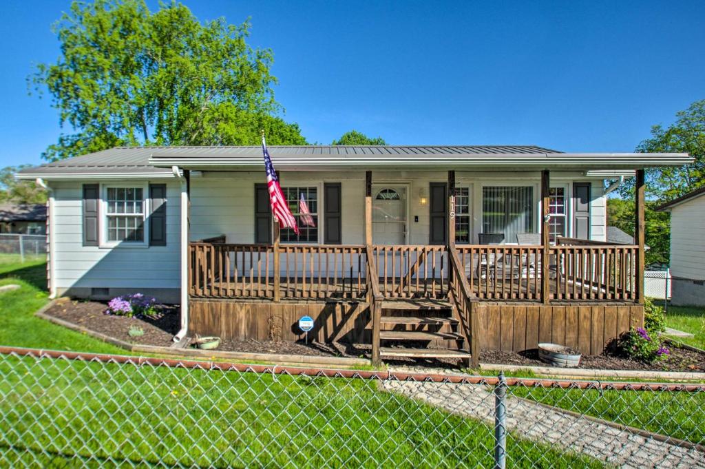 une petite maison dotée d'une terrasse couverte avec un drapeau. dans l'établissement Dog-Friendly Fayetteville Home with Hot Tub!, à Fayetteville
