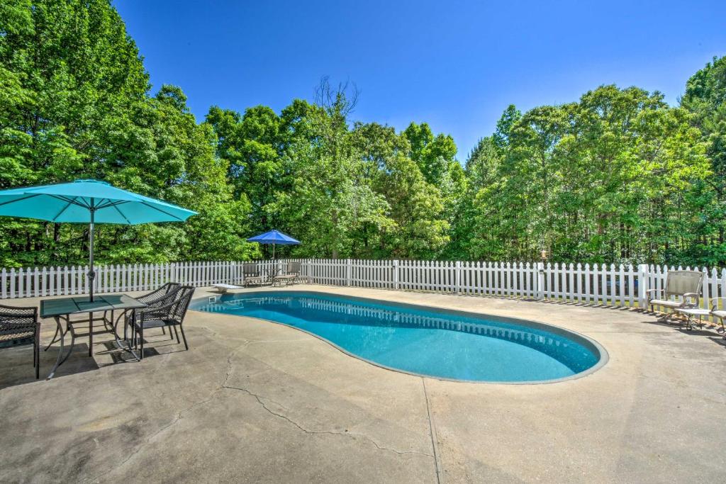 a pool with a table and chairs and an umbrella at Charming Ranch-Style Home Near Lake Lanier! in Gainesville