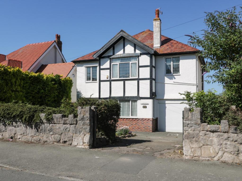 a white and black house with a stone wall at Burwood in Colwyn Bay