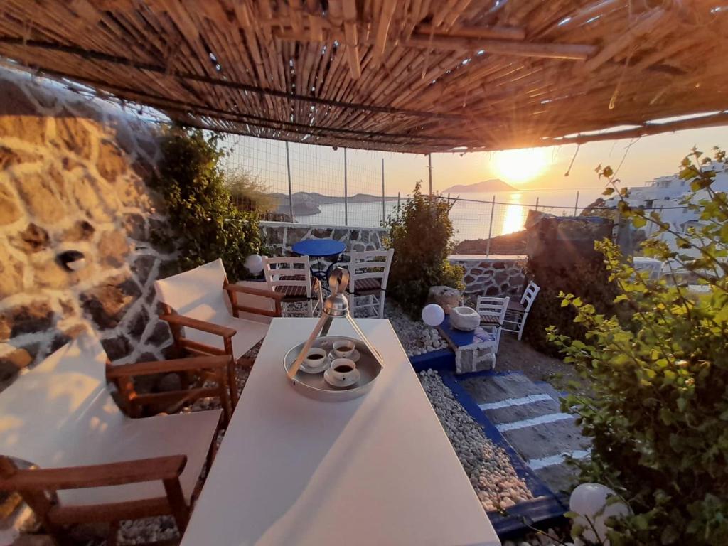 a patio with a table and chairs and the sun setting at Mamos Sunset House Plaka in Plaka Milou