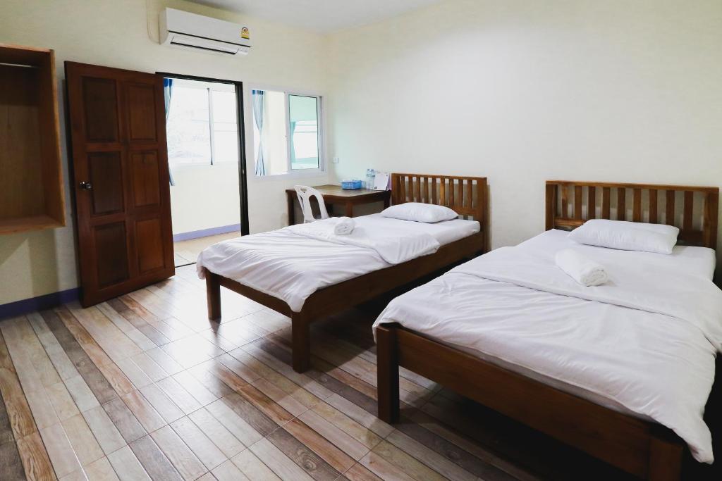 a bedroom with two beds and a door with a window at บ้านสวนชนะจน in Fang